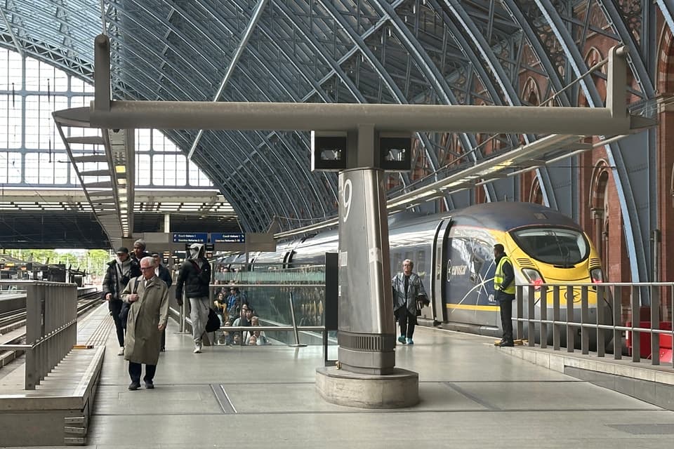 A Eurostar train waiting at a platform in London St Pancras International, under the ironwork arch of the station roof, with passengers walking along the platform